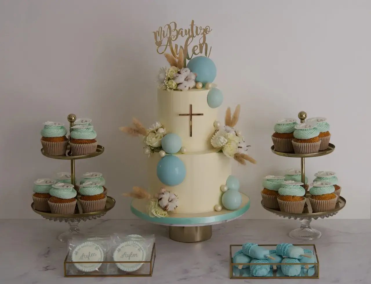 Originales tartas bonitas para un bautizo, con cupcakes, galletas y cakepops en tonos pastel y detalles dorados.
