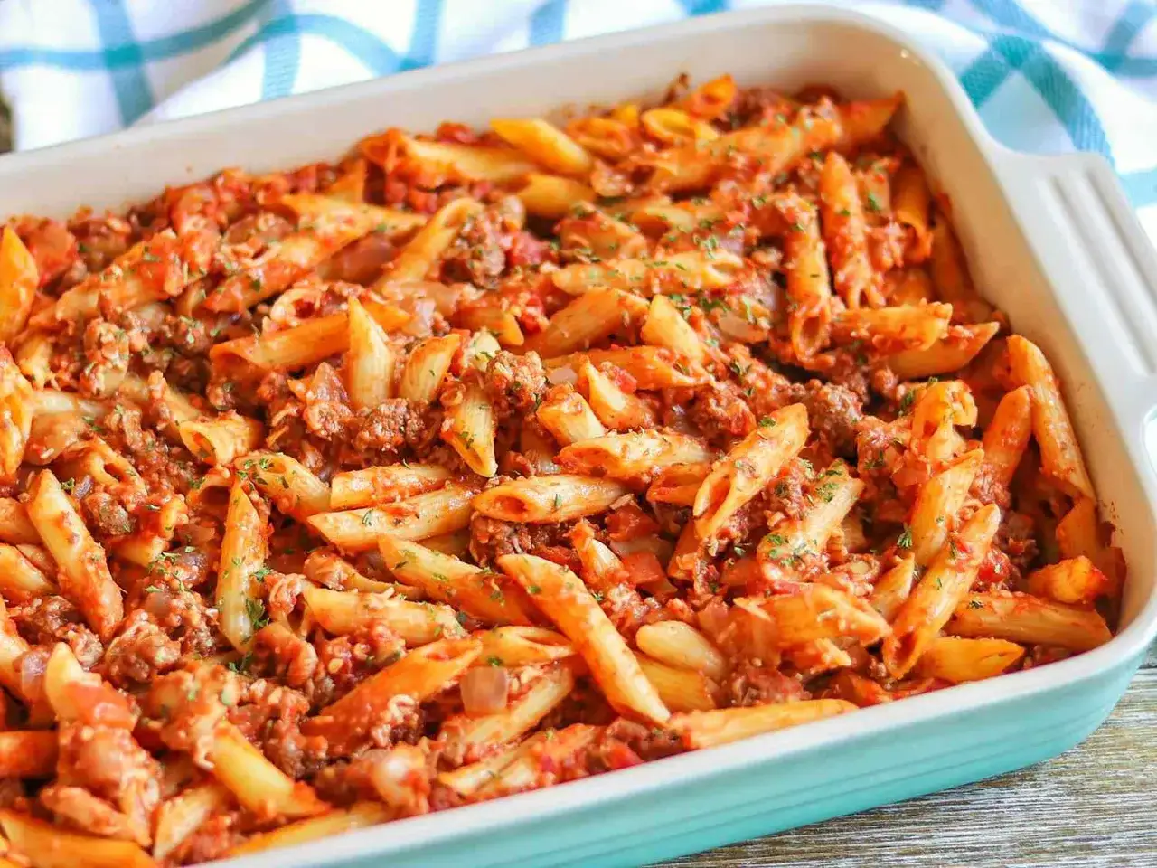 En ugnsbakad pastarätt med köttfärssås och penne, toppad med persilja. Perfekt för en mysig middag.