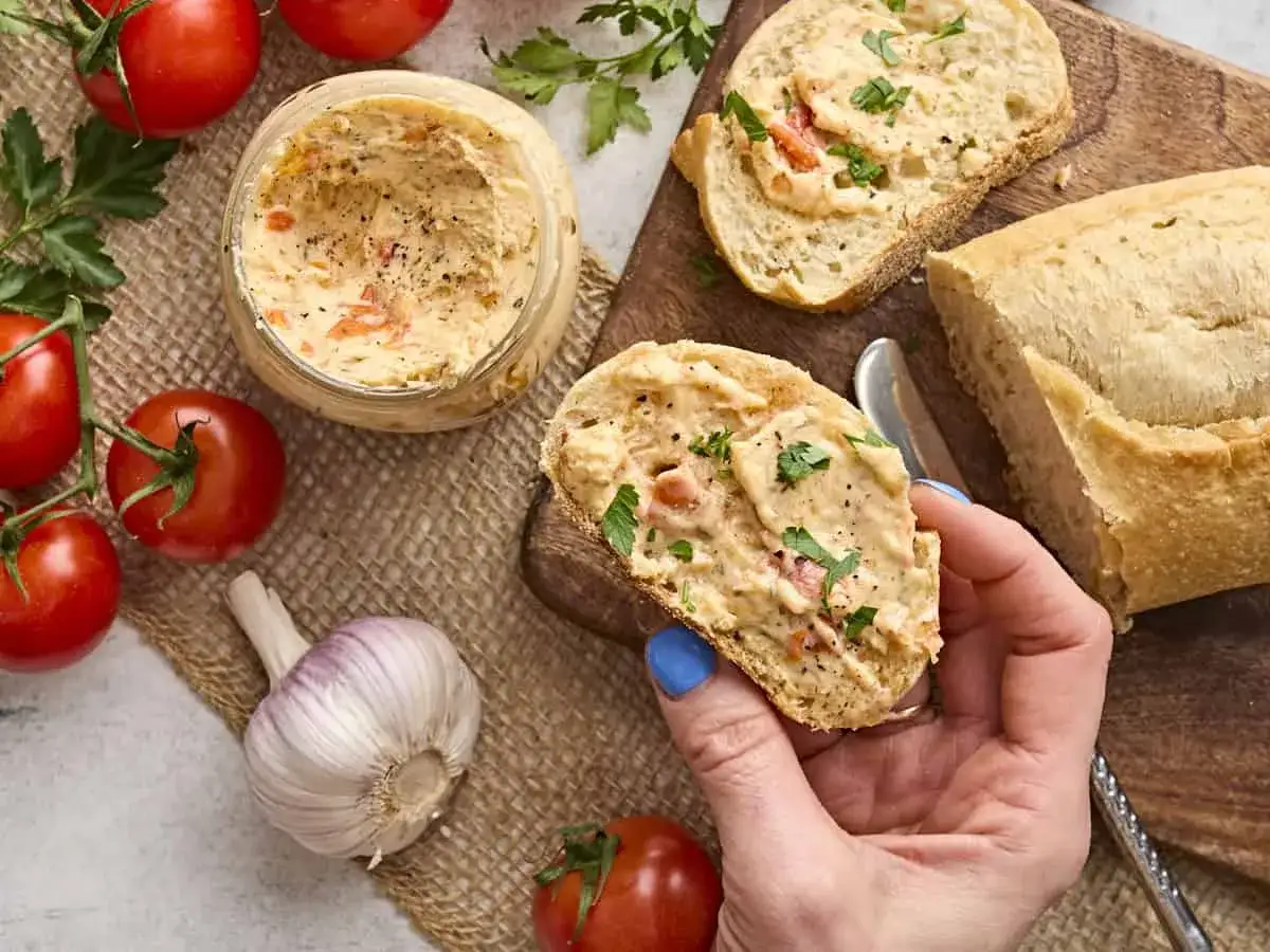 Selbstgemachte Tomatenbutter auf Brot, mit frischen Tomaten und Knoblauch daneben. Perfekt zum Dippen!