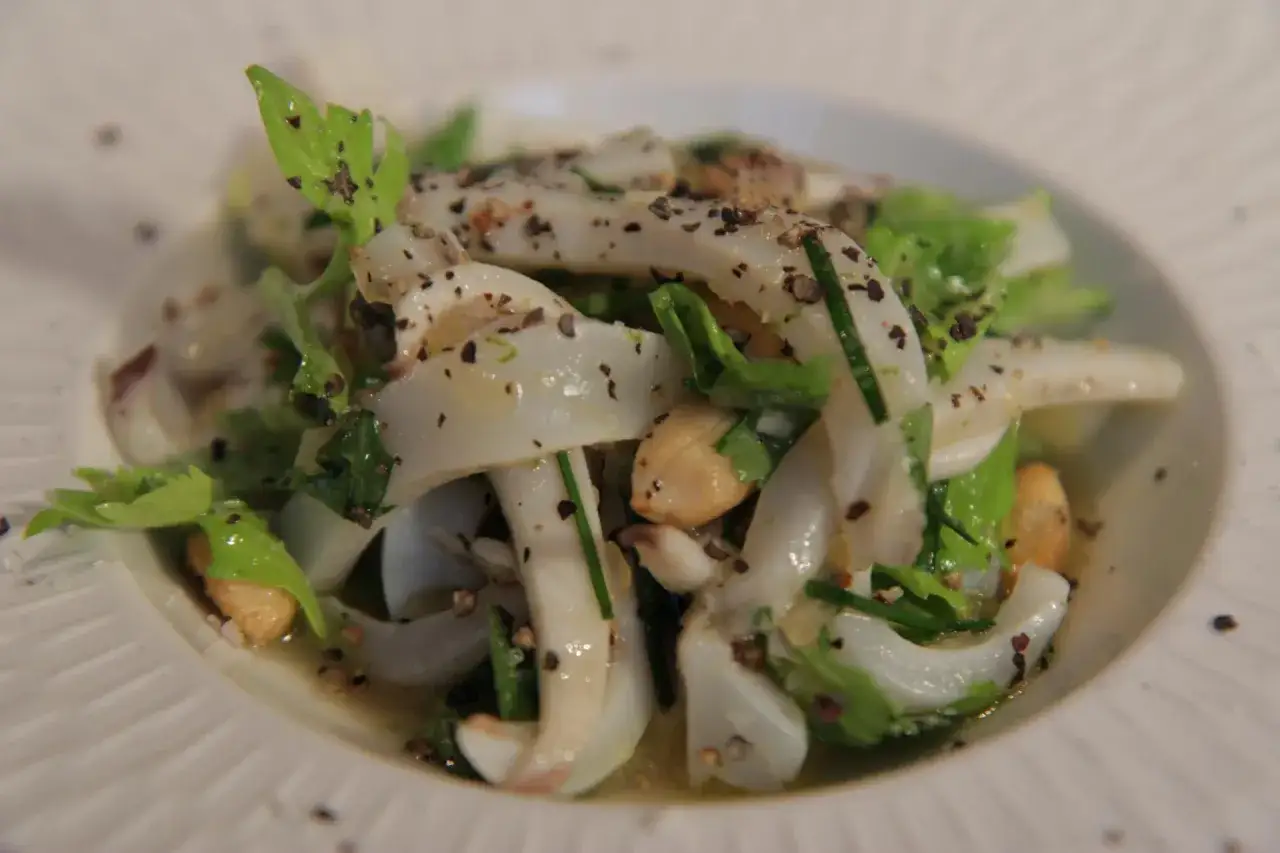 Salade de seiche coupée en lanières, assaisonnée de poivre et d'herbes fraîches. Parfait pour un temps de cuisson seiche au court-bouillon réussi.