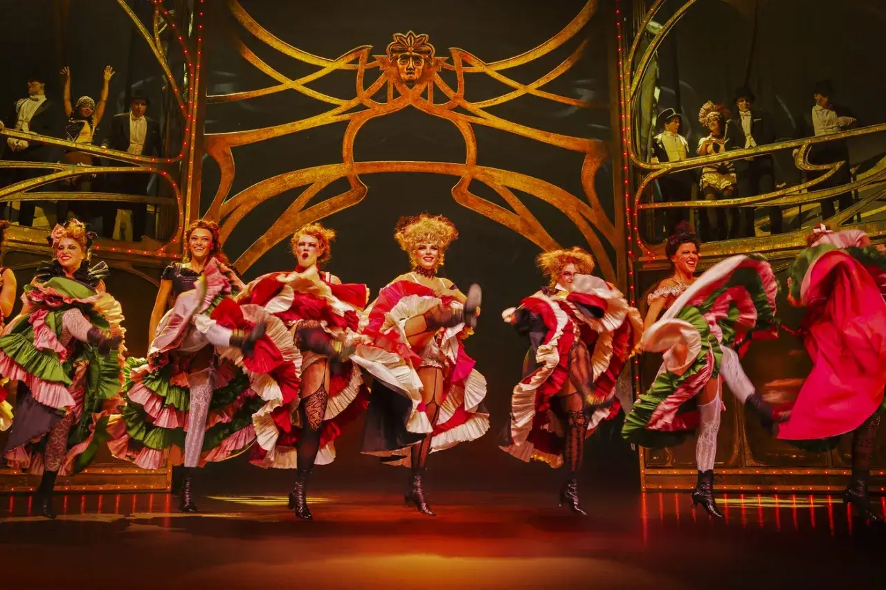 Dansare i färggranna, voluminösa klänningar utför en cancan-dans på scenen. En glimt av Moulin Rouge Stockholm.