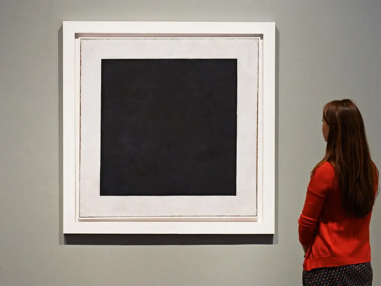 Eine Frau betrachtet ein schwarzes Quadrat, dessen Bedeutung zum Nachdenken anregt. Das Kunstwerk ist schlicht und doch eindringlich.