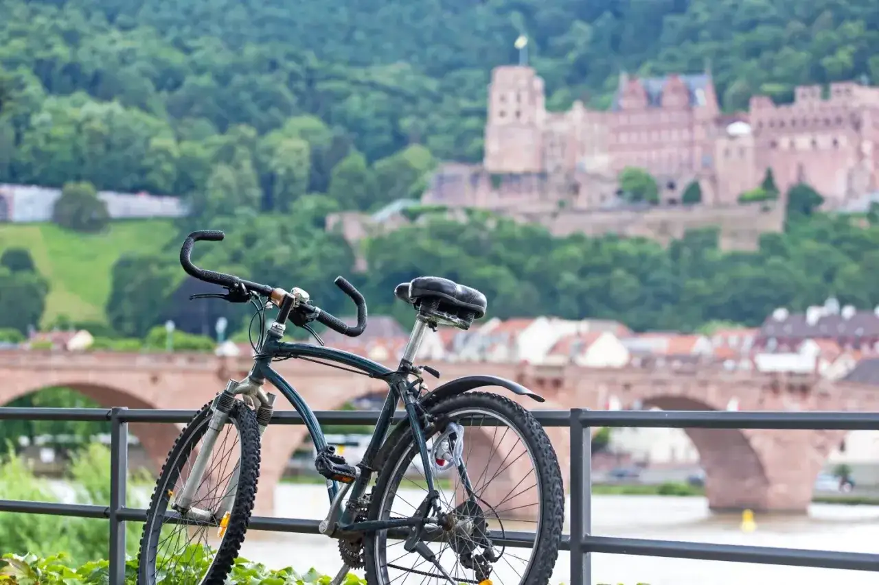Rower czeka na odkrywanie malowniczych tras rowerowych w Niemczech, z zamkiem Heidelberg w tle.