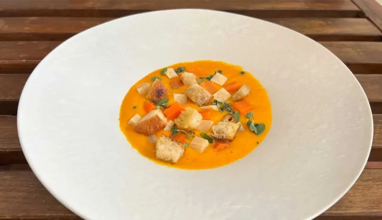 Vellutata di carote cremosa, guarnita con cubetti di carota, crostini dorati e erbe aromatiche fresche.