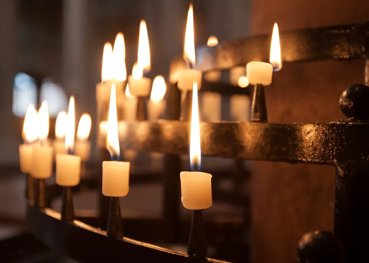 Flackernde Kerzen in einem Kerzenständer. Das warme Licht erinnert an die Bedeutung von Silvester und den Wunsch nach einem Neuanfang.