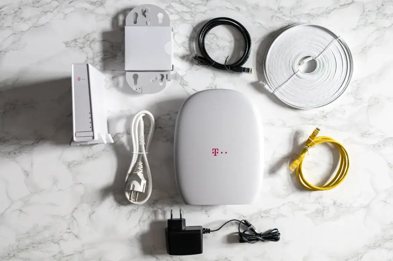 Zestaw do internetu bez limitu T-Mobile: router, zasilacz, kable Ethernet i uchwyt ścienny.