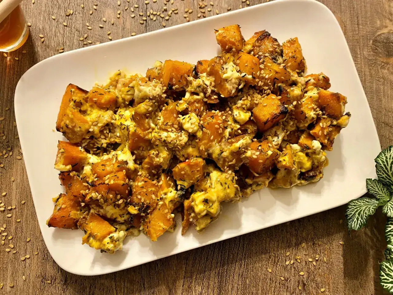 Délicieux potimarron au four, parsemé de graines de sésame et d'herbes, servi sur une assiette blanche.