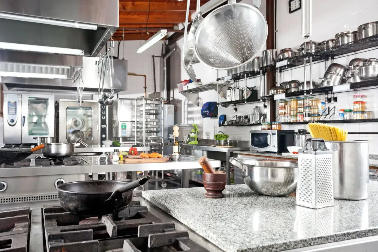 Cocina profesional lista para la acción: ollas, sartenes, verduras y pasta, todo en su sitio. Mise en place restaurante.