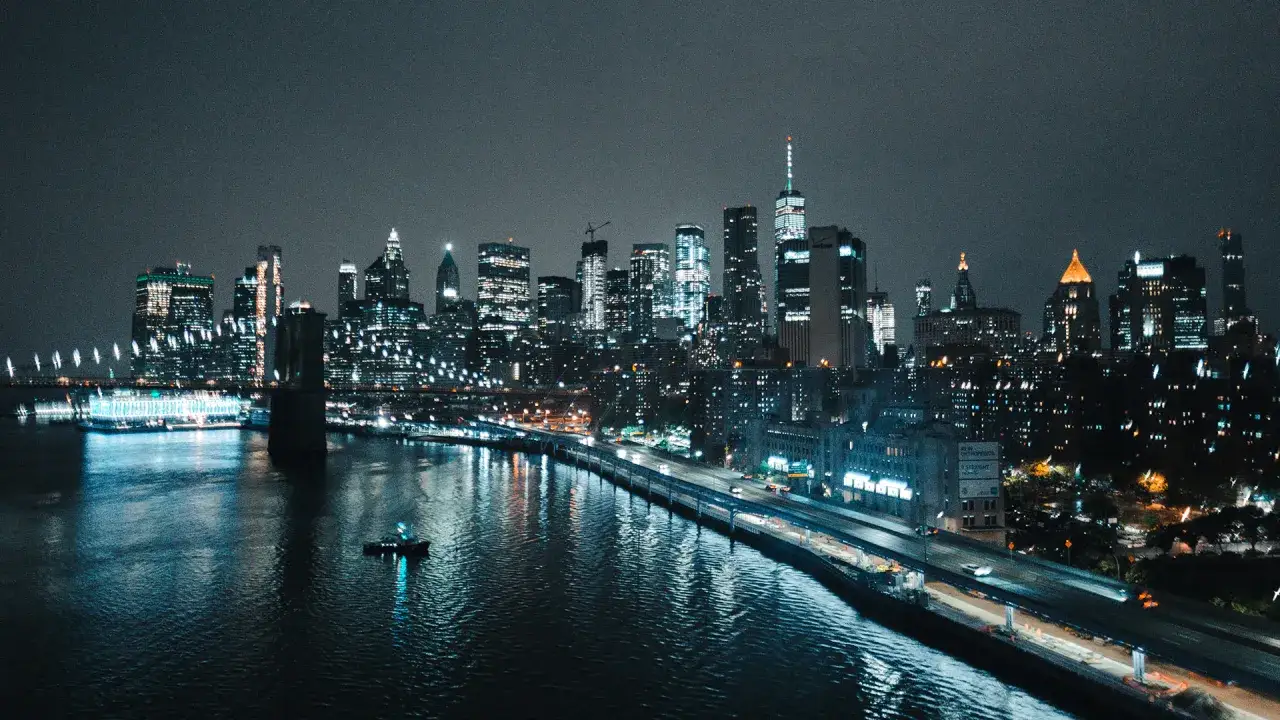 Vue panoramique de New York la nuit, avec le pont de Brooklyn illumin&eacute; et les gratte-ciel scintillants. Une iso photo nuit capturant la magie de la ville.