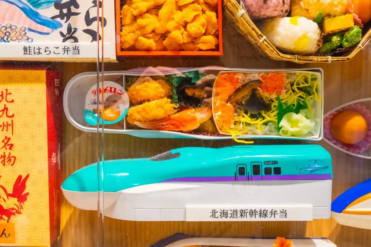 A train-shaped eki bento box with colorful Japanese food, including rice, seafood, and fried items.