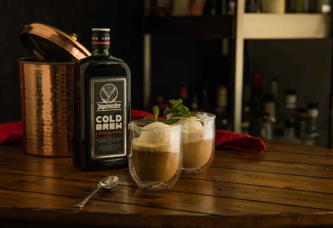 Dwa pyszne desery z lodami i kawą, obok butelka Jägermeister Cold Brew. Idealne na letnie popołudnie.