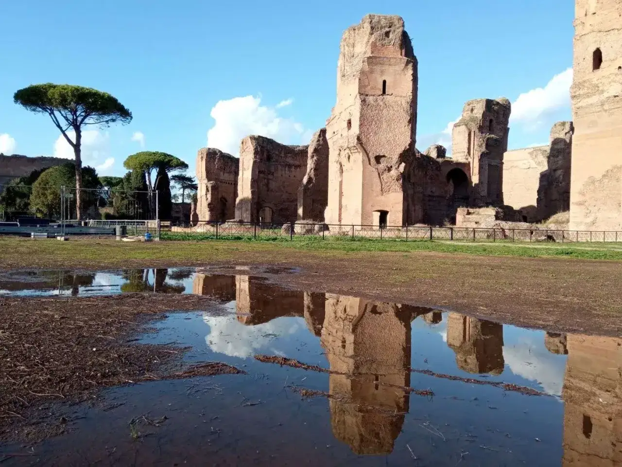 Rovine maestose delle Terme di Caracalla, con riflessi sull'acqua che evocano la loro antica storia.
