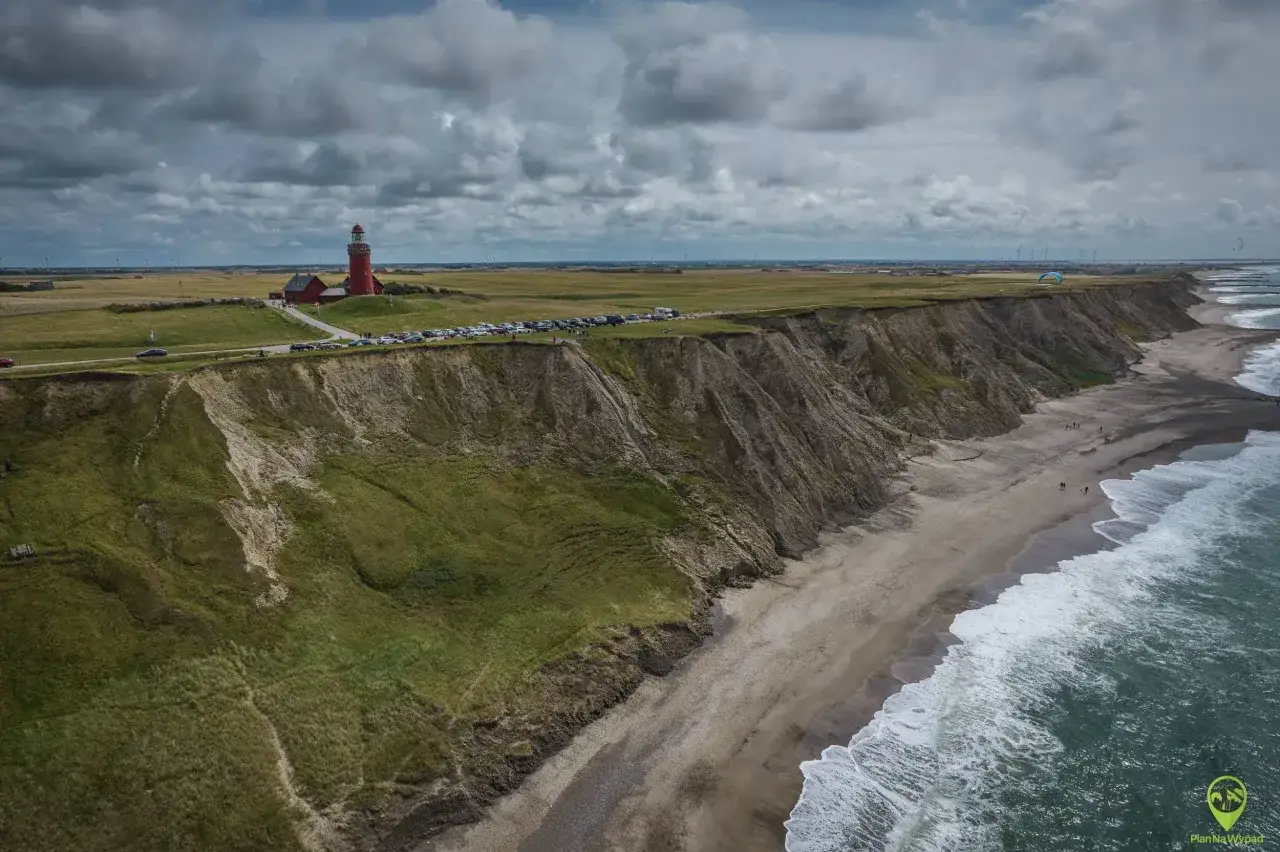 Wspaniałe wakacje w Danii! Czerwona latarnia morska góruje nad klifem, a plaża zaprasza do spacerów.