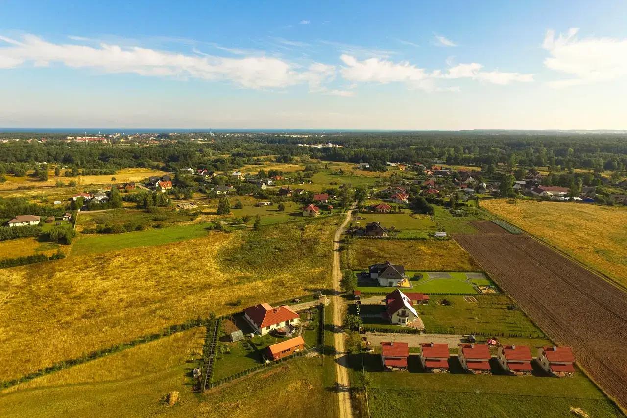 Widok z lotu ptaka na wieś z domami i polami. Może to być obrazek ilustrujący podatek za działkę budowlaną.