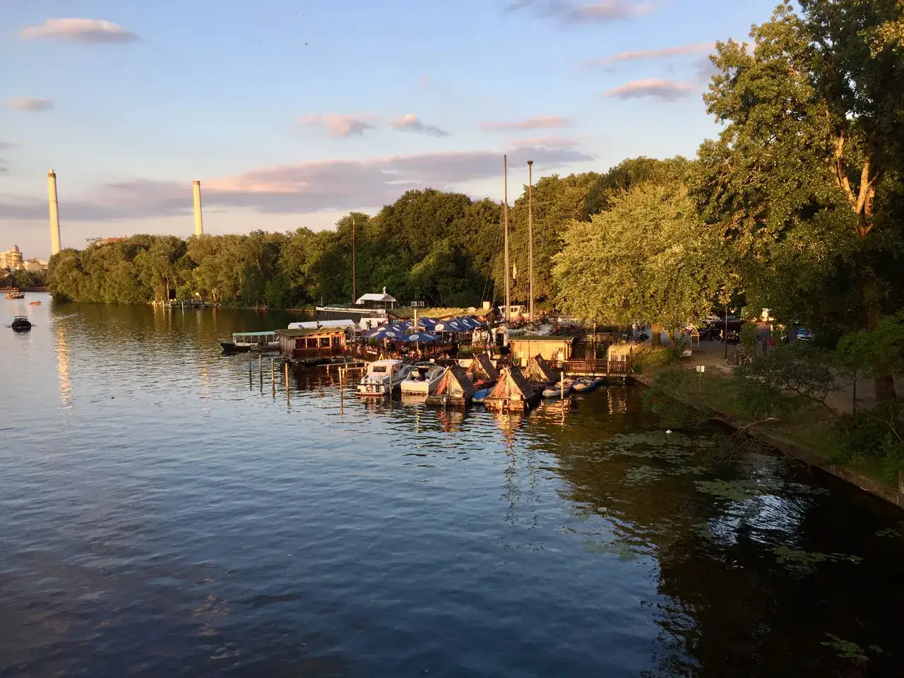 Boote und schwimmende H&auml;user liegen an einem Steg in einem der gr&uuml;nen Parks in Berlin.