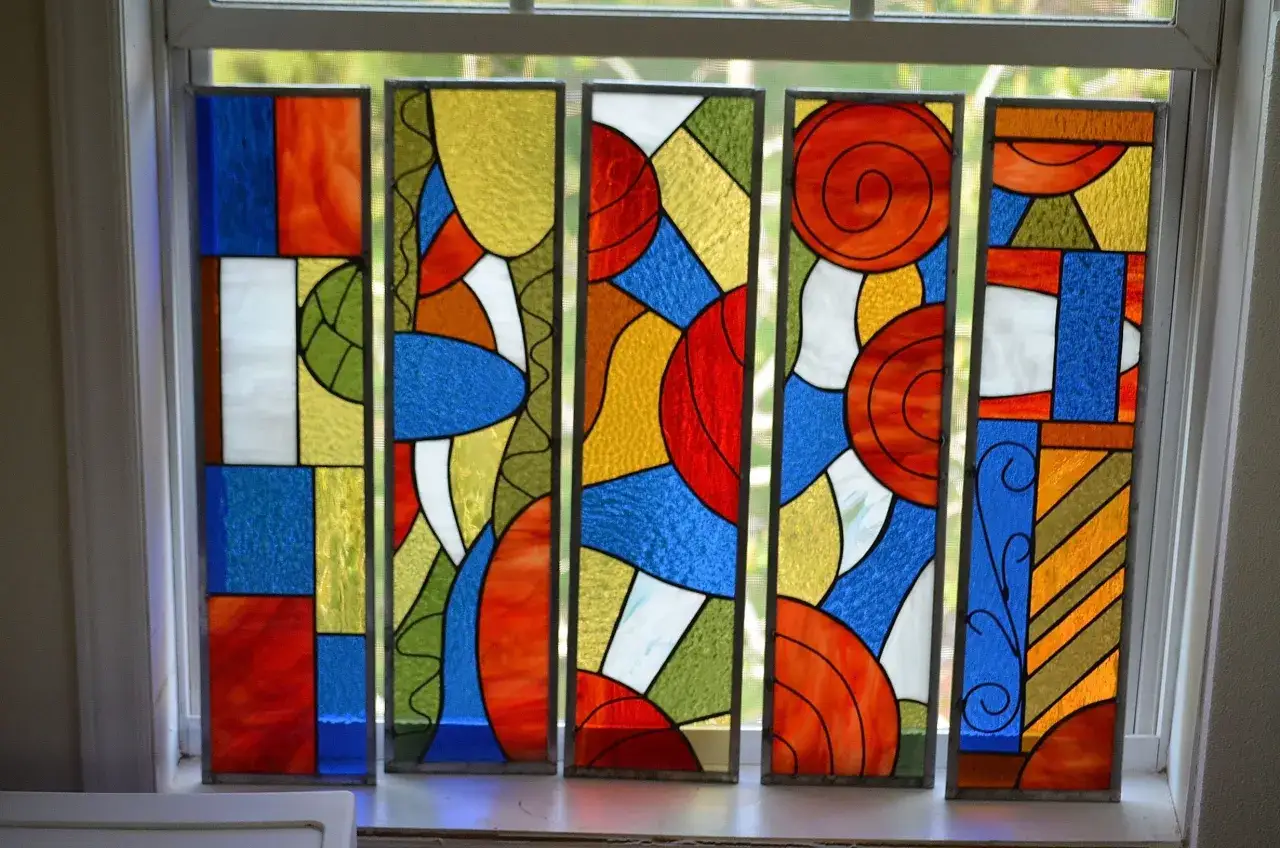 Cinq panneaux de vitrail moderne dessin abstrait aux couleurs vives : bleu, rouge, jaune, vert et blanc.