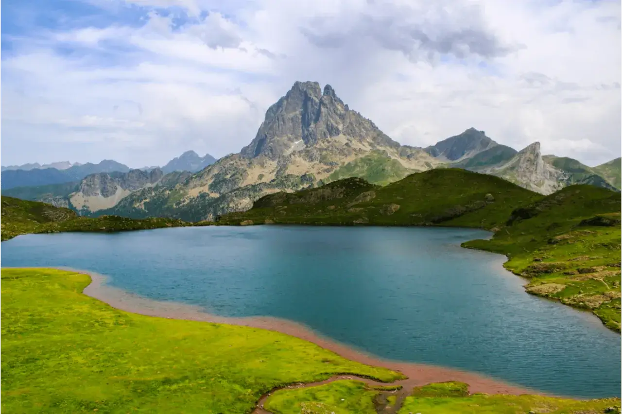 Lac d'altitude aux eaux bleues, entour&eacute; de montagnes verdoyantes et d'un pic rocheux imposant. Un paysage typique du GR10 dans les Pyr&eacute;n&eacute;es-Orientales.