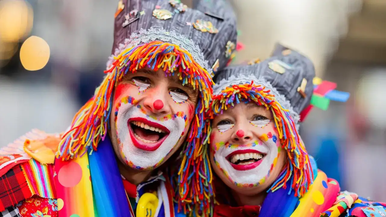 Zwei lachende Clowns mit bunten Per&uuml;cken und Schminke, bereit f&uuml;r den Fasching 2027.