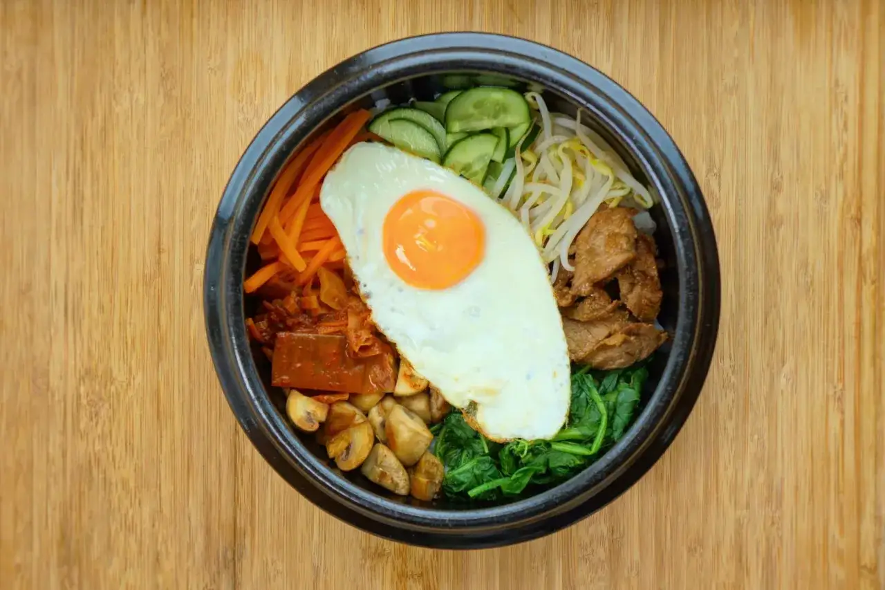 Kolorowy bibimbap z jajkiem sadzonym, wołowiną, warzywami i grzybami. Idealny przepis na szybki obiad.