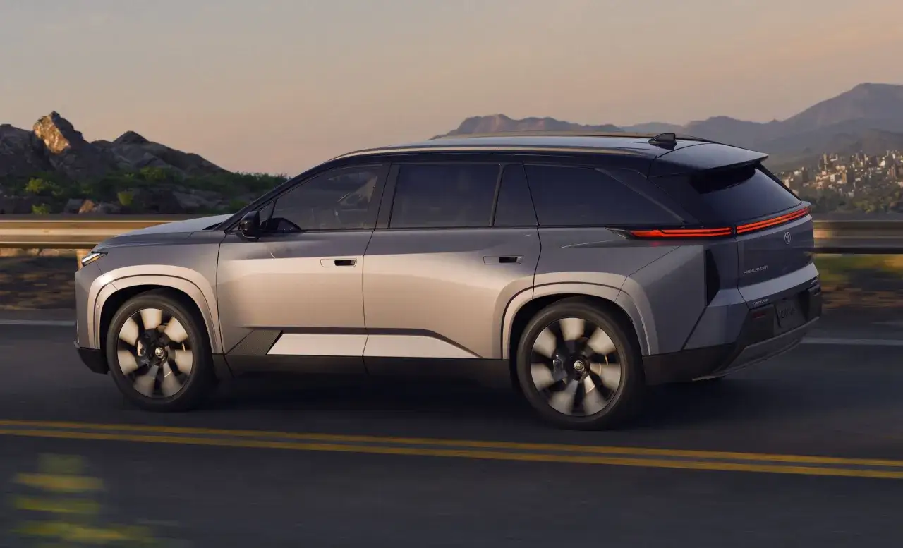 Nowy Toyota Highlander w ruchu, z widokiem na góry i miasto. Sprawdź atrakcyjną toyota highlander cena.