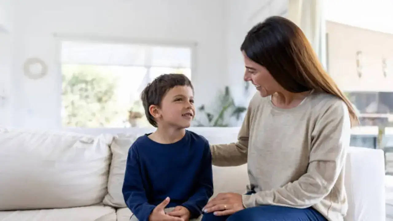 Una madre sonr&iacute;e a su hijo, compartiendo un momento tierno. Ella le pone una mano en el hombro, demostrando c&oacute;mo ser una buena madre con amor y conexi&oacute;n.