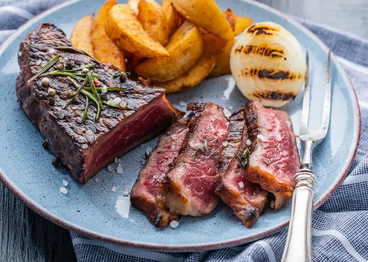 Un jugoso entrecot a la plancha, cortado en rodajas, acompa&ntilde;ado de patatas r&uacute;sticas y cebolla a la parrilla. &iexcl;Un fest&iacute;n para los sentidos!