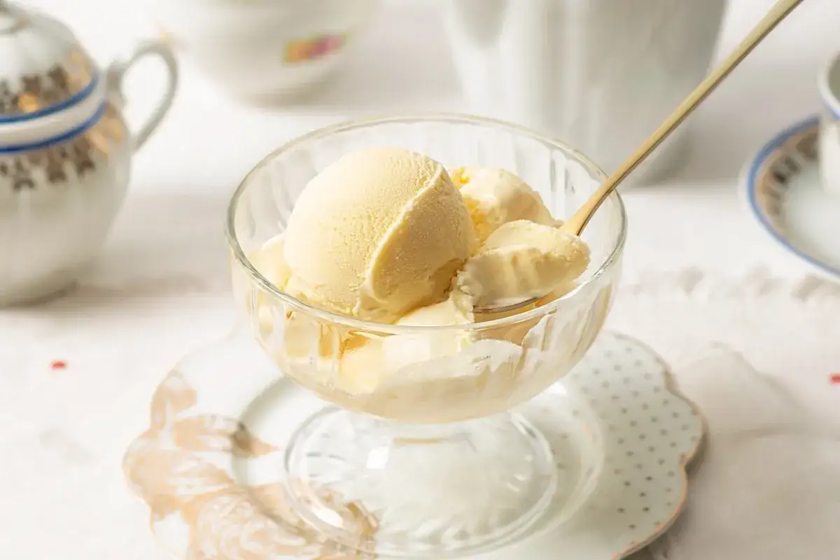 Copa de cristal con helado de mantecado cremoso, servido con una cuchara dorada.