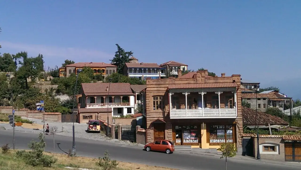 Urokliwe uliczki Telavi, Gruzja, z tradycyjną architekturą i balkonami. Pomarańczowy samochód jedzie po drodze.