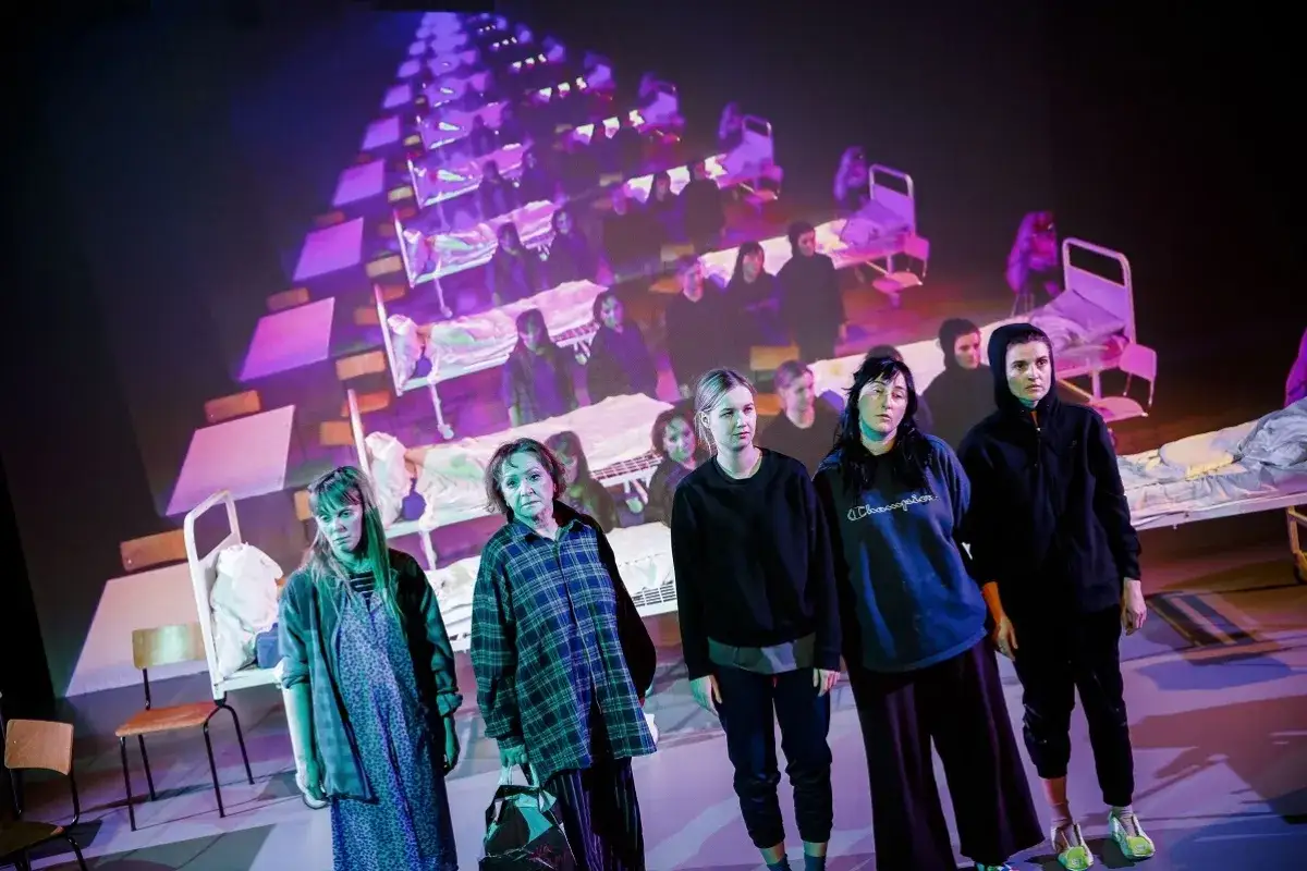 Na scenie teatru, w tle projekcja łóżek szpitalnych, stoi grupa kobiet. To moje rok relaksu i odpoczynku, choć wygląda na trudny.