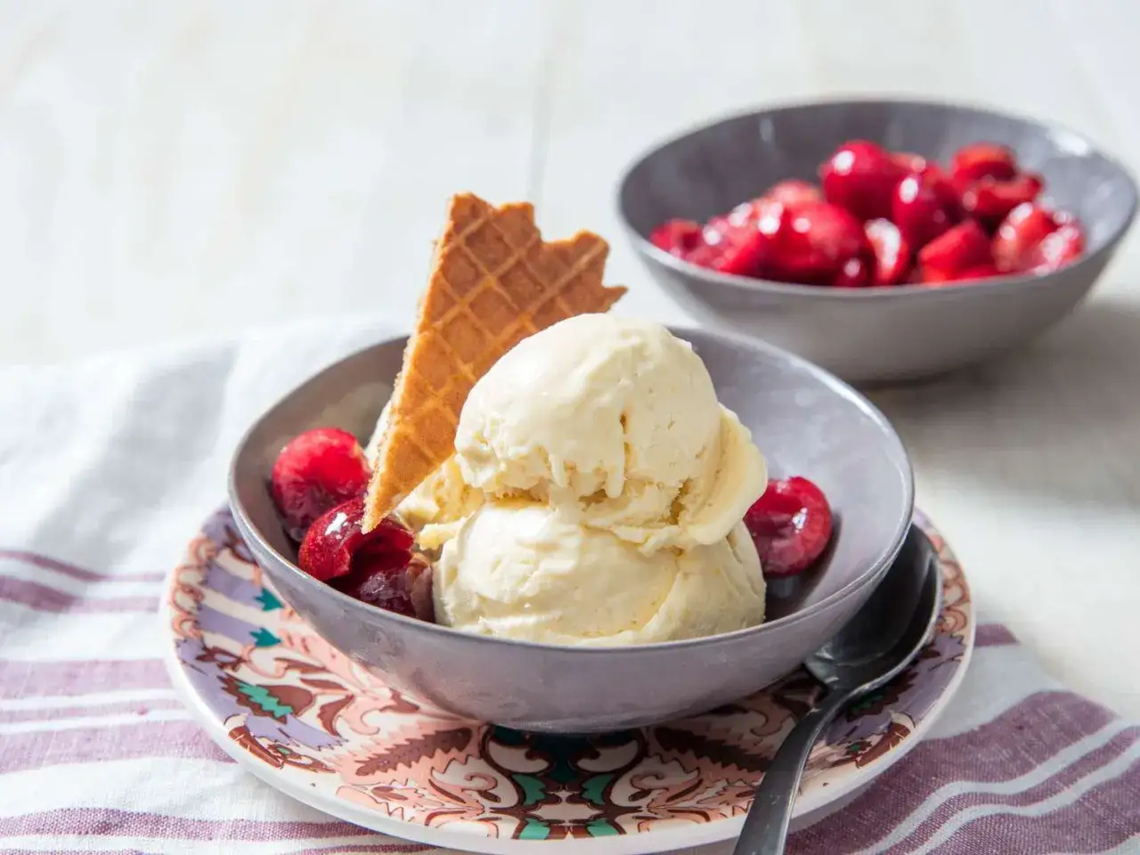 Cremiges Mascarpone Eis mit Kirschen und Waffelstückchen in einer Schale.
