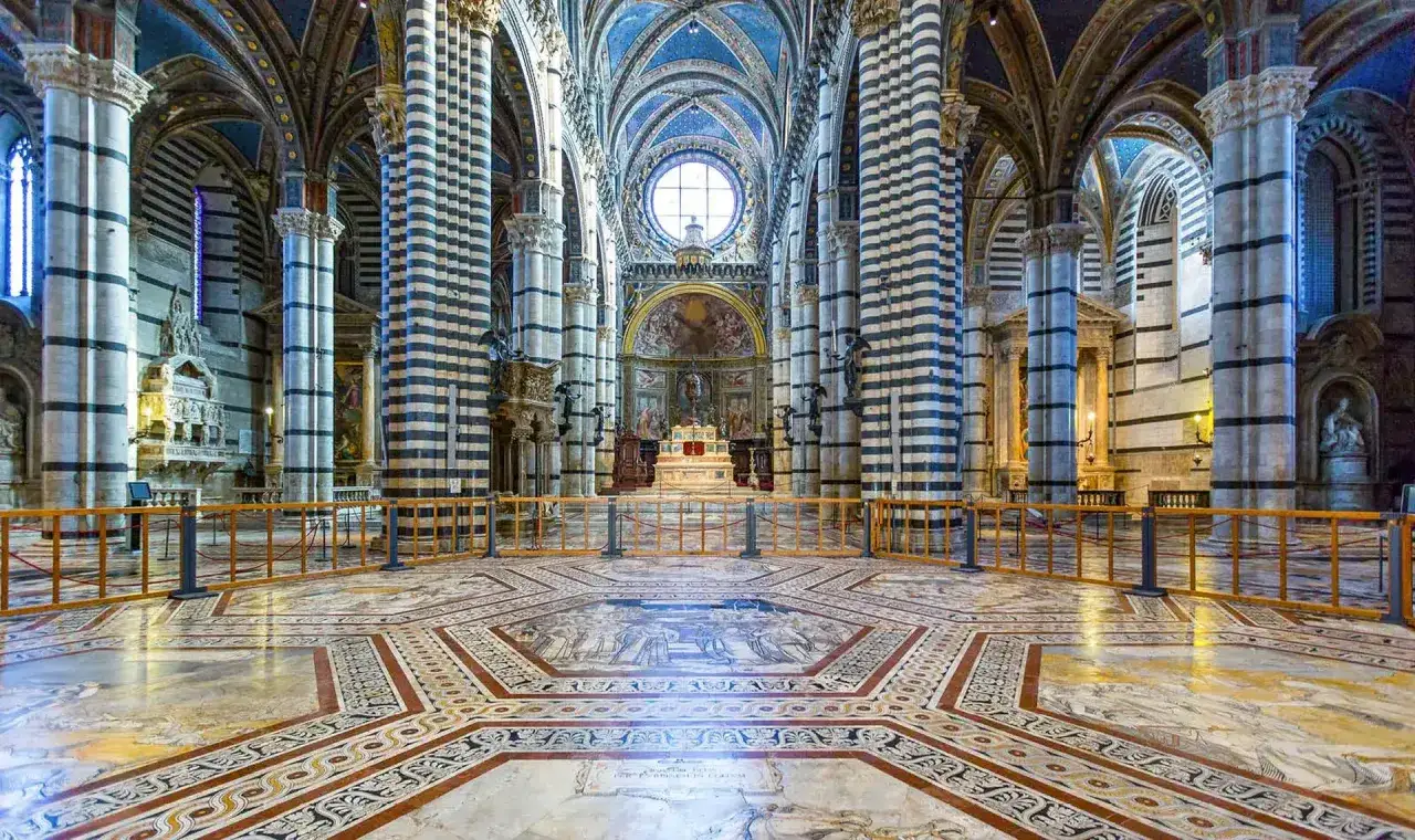 Interno del Duomo di Siena, un capolavoro da vedere assolutamente. Colonne a strisce, soffitto blu stellato e un pavimento intarsiato mozzafiato.