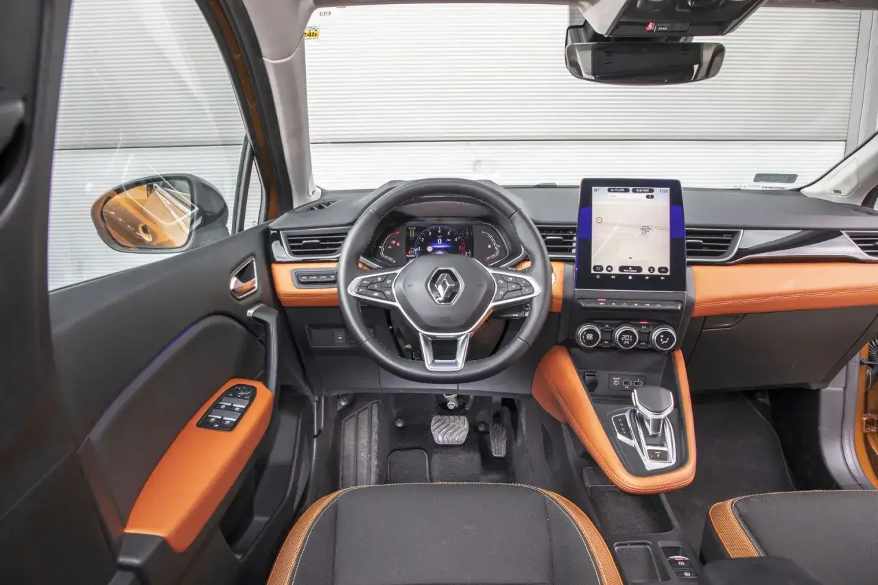 Wnętrze Renault Captur 2019 z pomarańczowymi akcentami, cyfrowym kokpitem i ekranem multimediów.