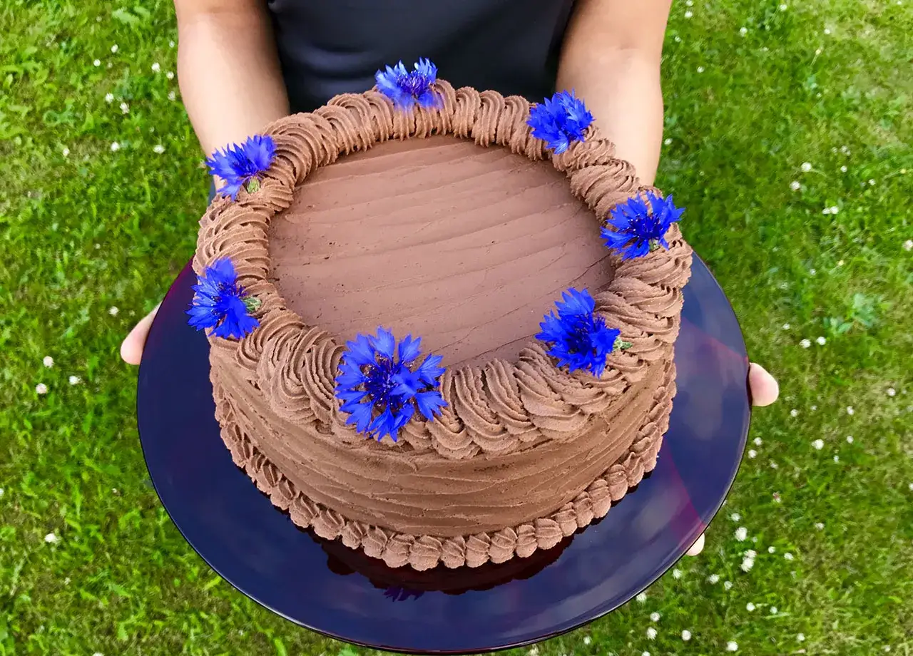 En vacker chokladgr&auml;dde t&aring;rta med bl&aring; kornblommor, perfekt f&ouml;r en sommarfest i tr&auml;dg&aring;rden.