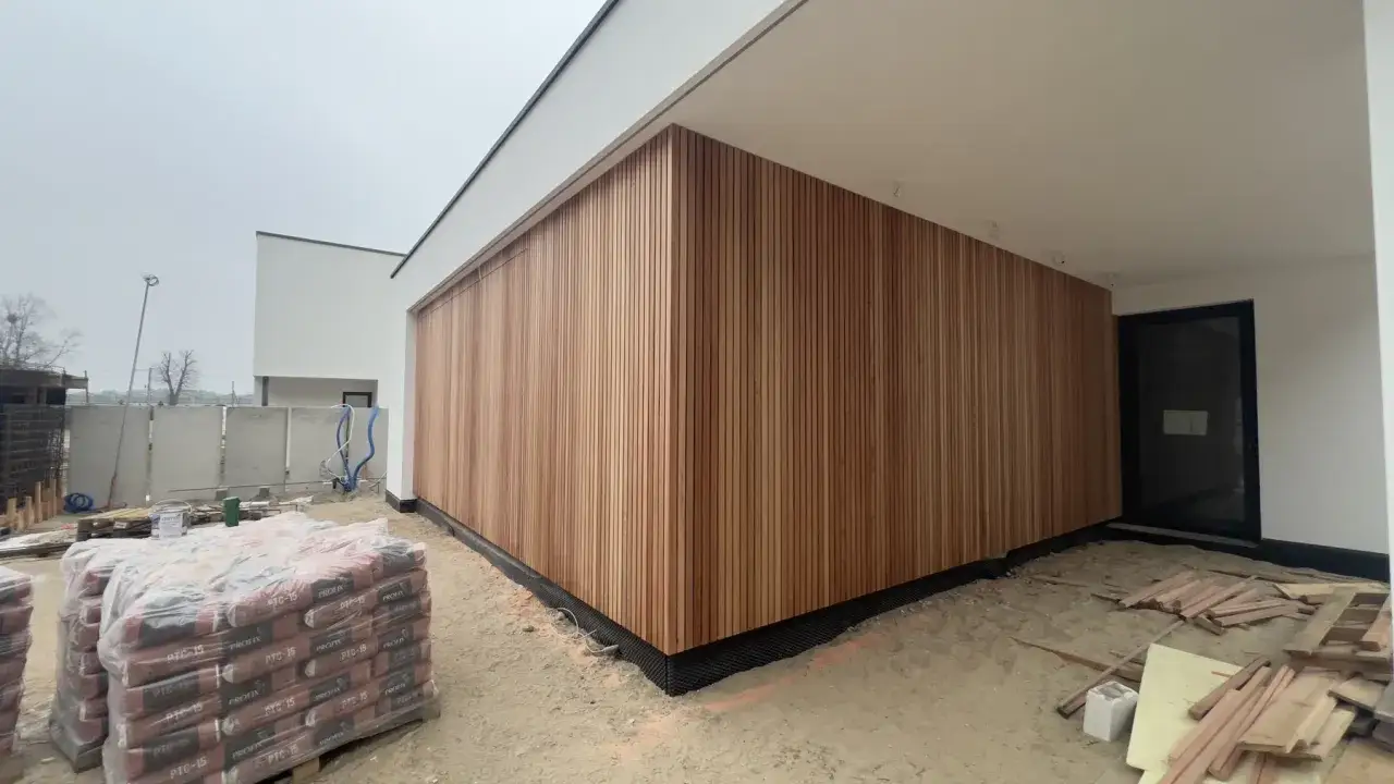 Nowoczesna elewacja z pionowej sklejki drewnianej, podkreślająca architekturę budynku.
