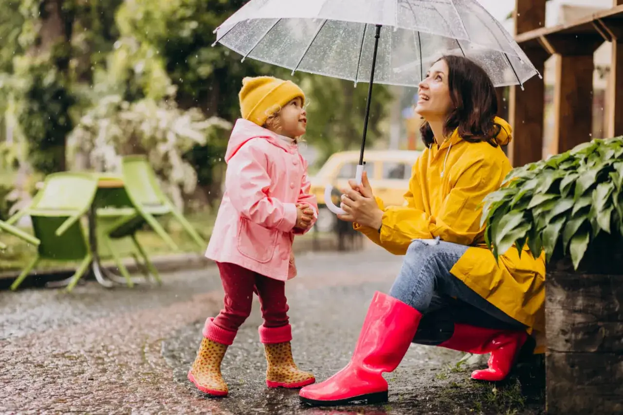 Mama i dziecko pod parasolem w deszczu. Nawet w niepogodę Szczyrk oferuje atrakcje, jak wspólne zabawy na świeżym powietrzu.