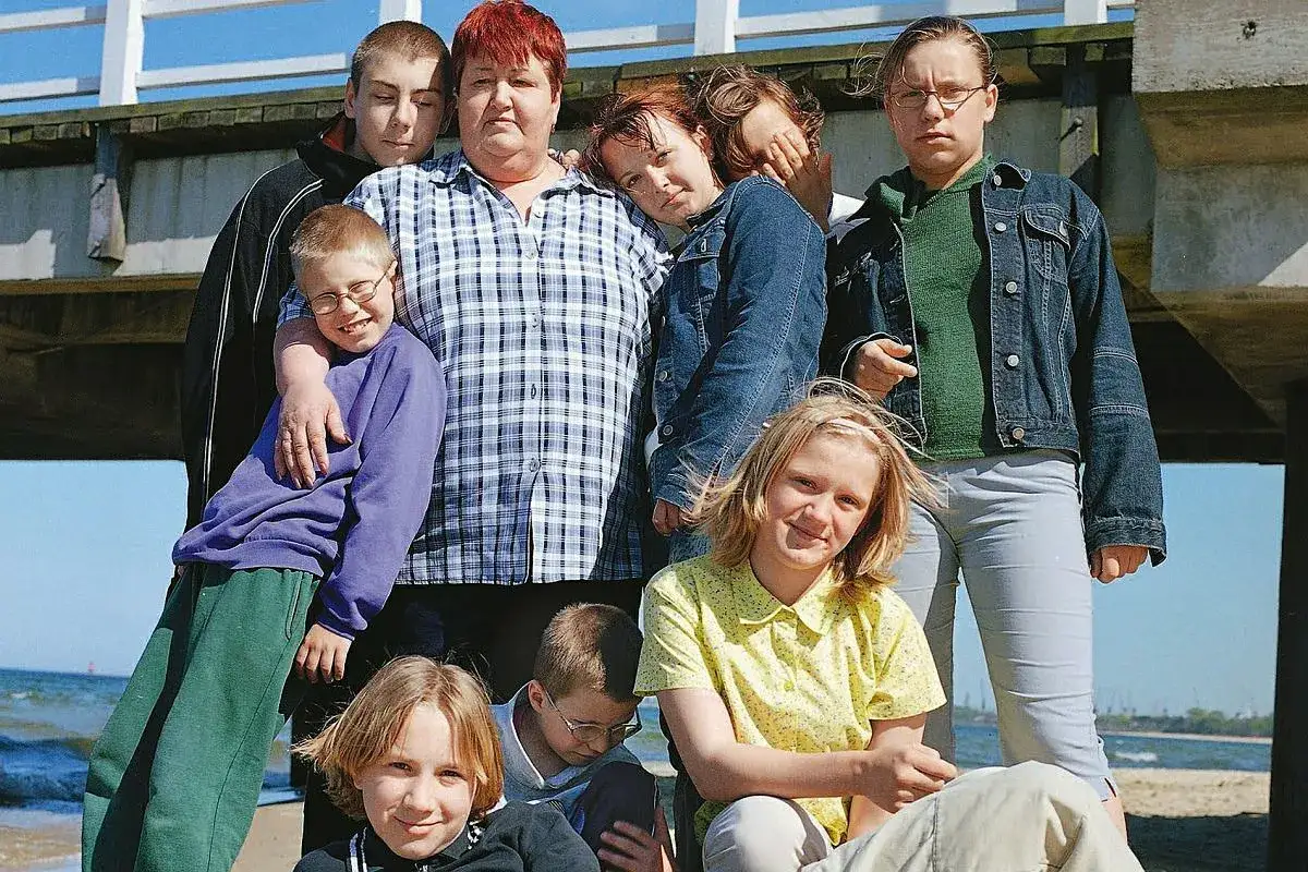 Krzysztof, w wieku 10 lat, uśmiecha się, otoczony rodziną na plaży.