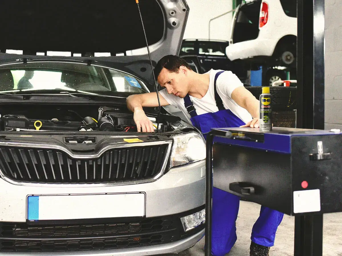 Mecánico trabajando en el motor de un coche para cambiar un faro.