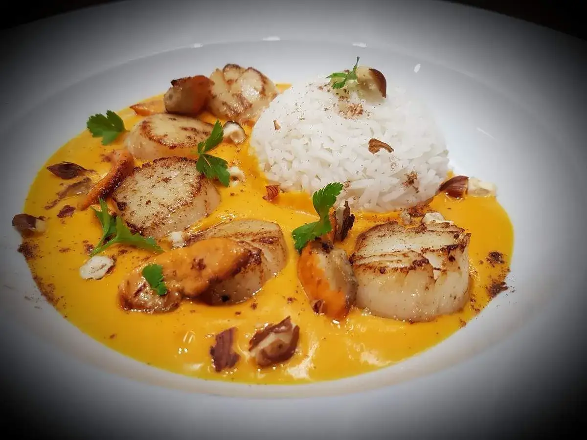 Saint-jacques po&ecirc;l&eacute;es sur un lit de cr&egrave;me de butternut, accompagn&eacute;es de riz blanc et de quelques &eacute;clats de noisettes.