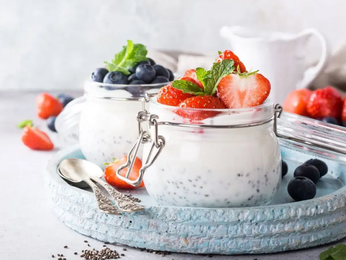 Två burkar chiapudding med färska jordgubbar och blåbär, perfekt för ett hälsosamt chiapudding recept.