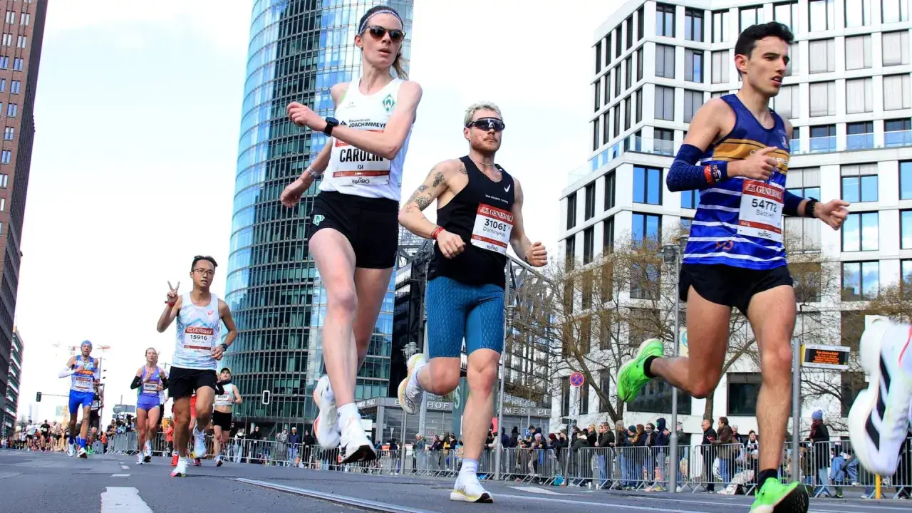 Läufer auf der Halbmarathon Distanz in Berlin, mit modernen Hochhäusern im Hintergrund.