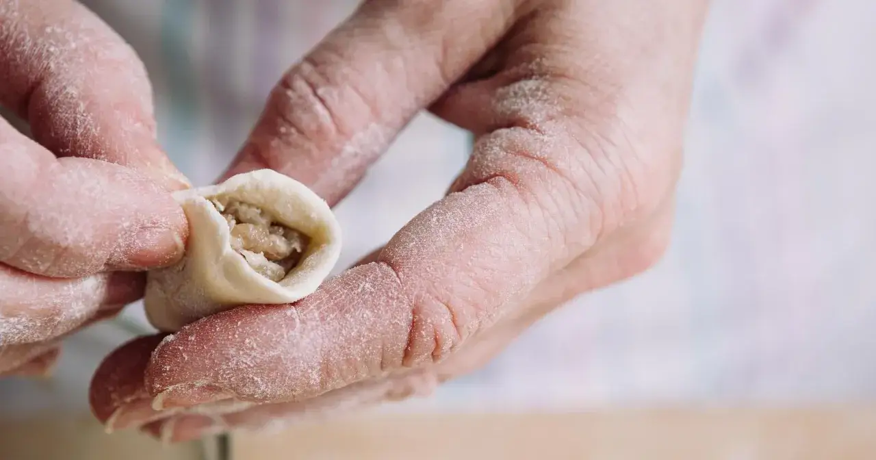Dłonie z mąką lepią pierogi. Tradycyjny przepis na pyszne, domowe pierogi.