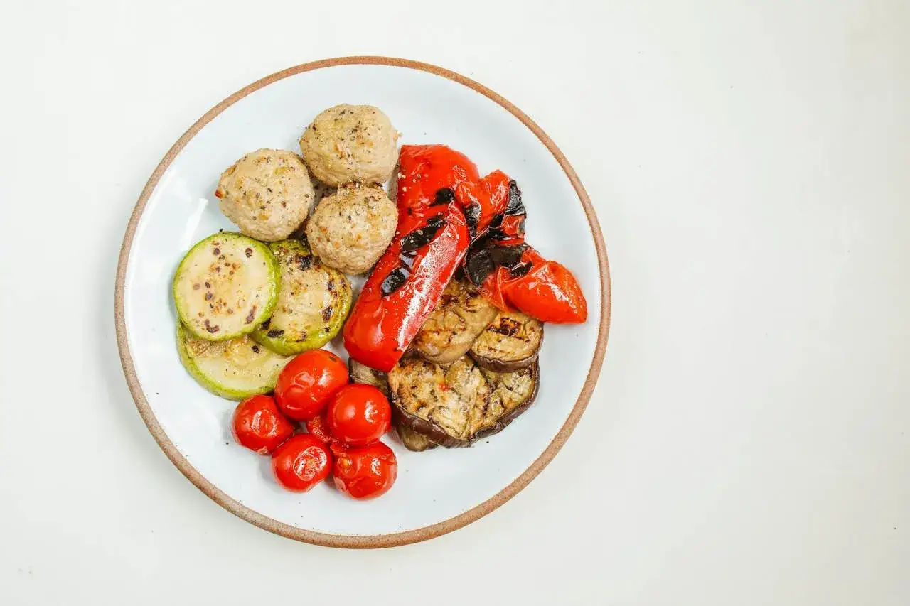 Polpette tonno e ricotta su un piatto con verdure grigliate: zucchine, melanzane, peperoni rossi e pomodorini.