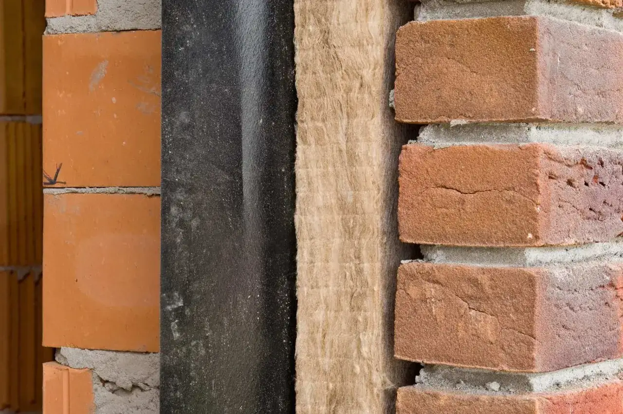 Warstwy termoizolacji budynku: cegła, czarna membrana, wełna mineralna i cegła klinkierowa.