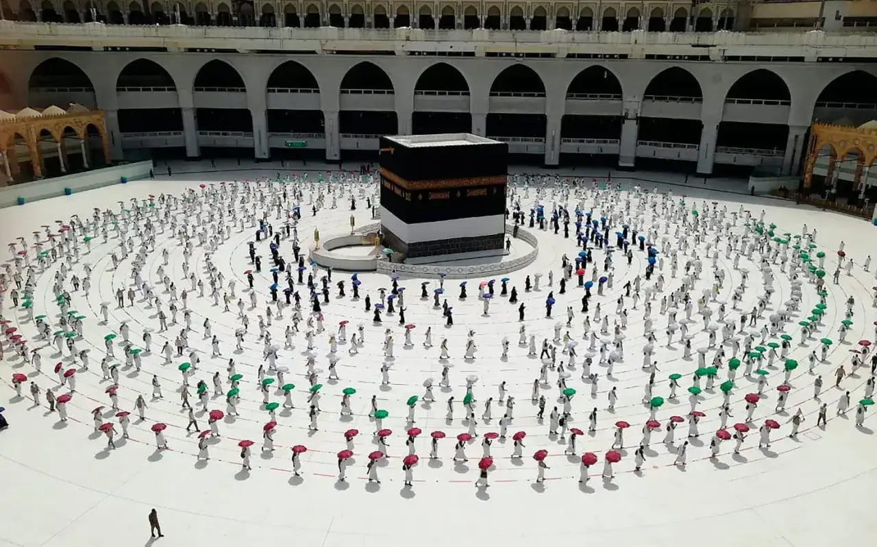 M&aring;nga pilgrimer cirklar runt den heliga byggnaden i Mecka, vissa med f&auml;rgglada paraplyer som skydd.