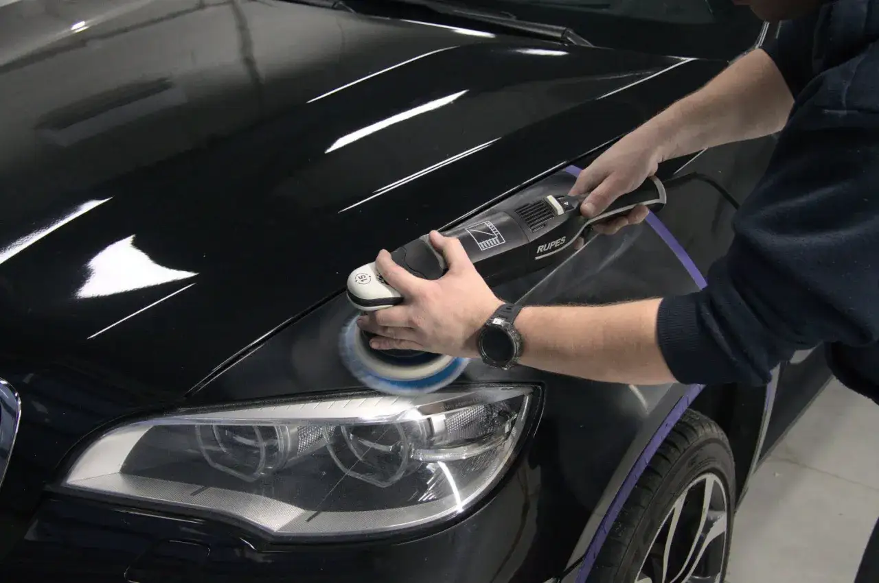 Profesjonalne polerowanie lakieru samochodowego czarnym BMW. Maszyna Rupes usuwa rysy, przywracając blask.