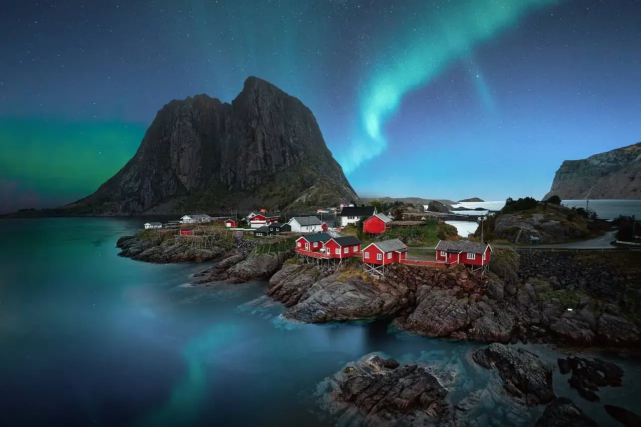 Lofoten Winter: Rote Fischerh&uuml;tten am Fjord unter dem Nordlicht und Sternenhimmel.
