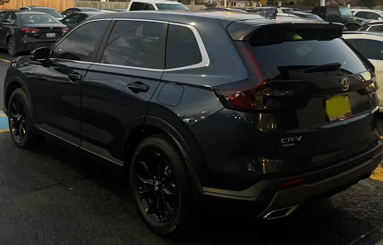 Mörkblå Honda CR-V med svarta fälgar. En bil som verkar ha ett **honda cr-v problem** med sin parkering, nära en gul linje.