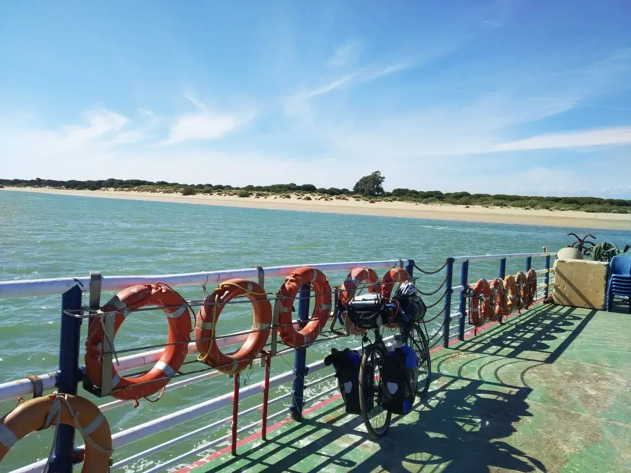 F&auml;hrfahrt bei Sanl&uacute;car de Barrameda. Rettungsringe und ein beladenes Fahrrad auf dem Deck, mit Blick auf die K&uuml;ste.