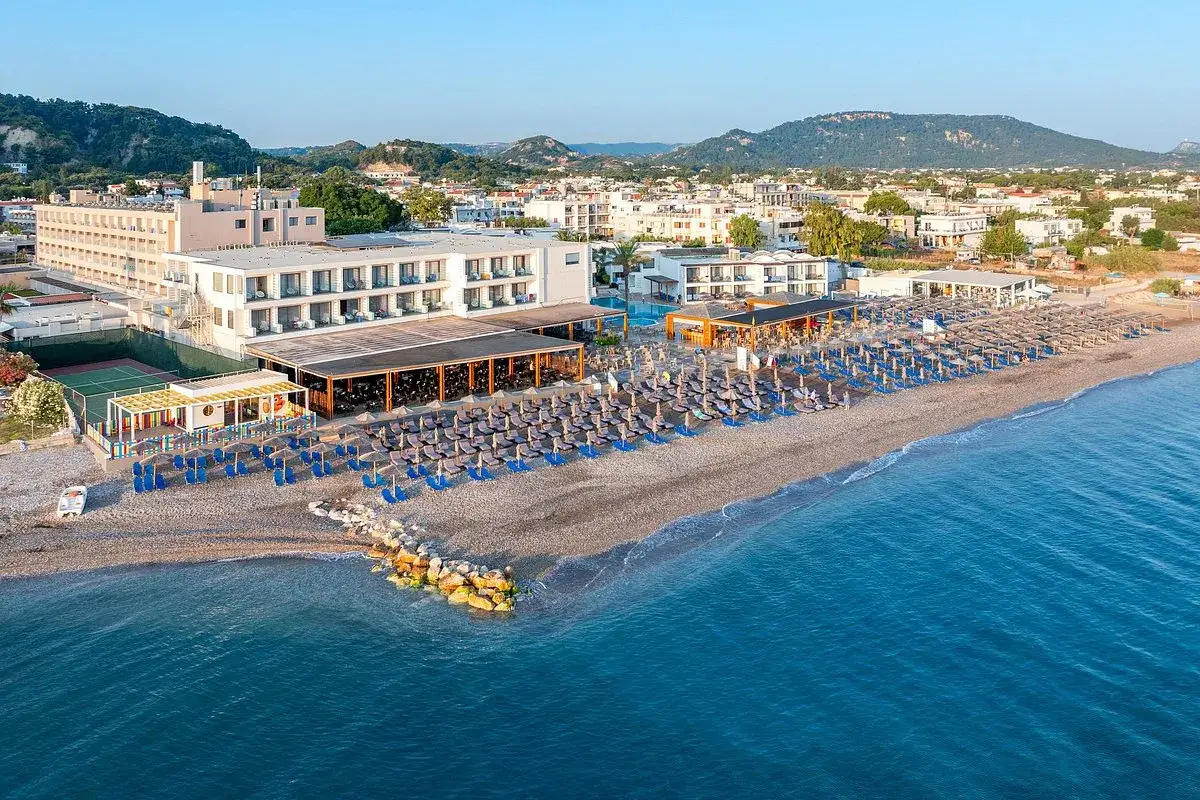Słoneczny dzień nad Ialyssos Bay. Hotel z basenem i plażą pełną leżaków zaprasza do wypoczynku.