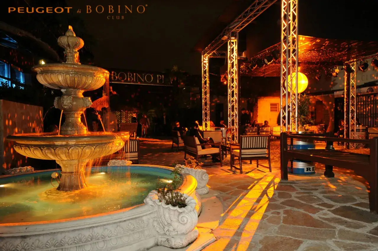 Fontana illuminata e sedute all'aperto in un locale notturno, tra le discoteche a Milano.